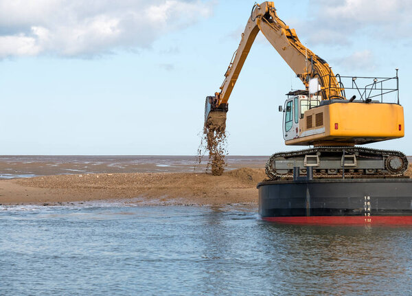 Barge mounted dredger digging out a coastal channel