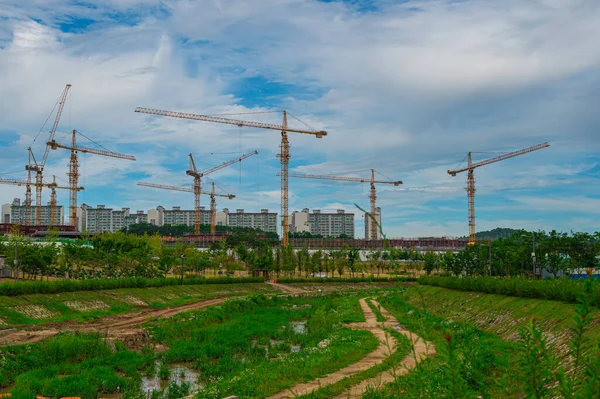 korea buiding modern construction site with  cranes . Tower crane work on a construction site lifts a load at high-rise building. Summer blue sky with fluffy clouds on the background