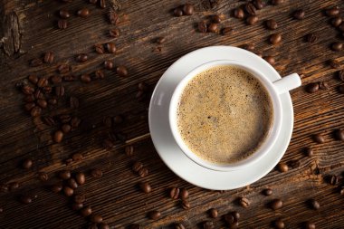 Beyaz fincan kahve vintage ahşap bir masa üzerinde duran üzerinde birkaç kahve çekirdekleri ile 