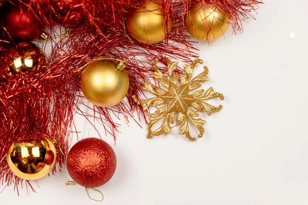New Years composition. Christmas red and yellow balls decorations and New Years fluffy red tinsel and golden snowflake on a white background. — Stock Photo, Image