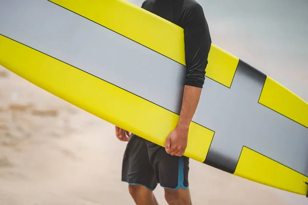 Молодой серфер держит желтую доску для серфинга на пляже Калифорнии. Водные виды спорта . — стоковое фото