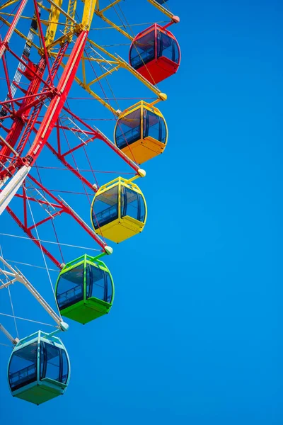 A big colourful ferris wheel isolated on blue sky background in amusement park. Summer family vacation concept. — Stock Photo, Image