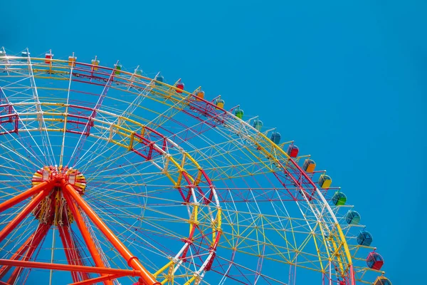 Une grande roue ferris colorée isolée sur fond de ciel bleu dans un parc d'attractions — Photo