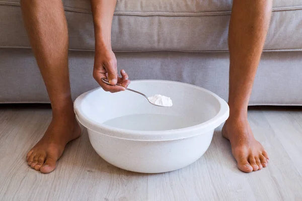 Man making relaxing feet bath with baking soda at home. — Stock Photo, Image