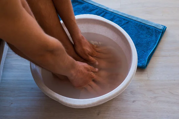 Pria meletakkan tangan dan kaki di kamar mandi dengan air panas dan baking soda di rumah. — Stok Foto