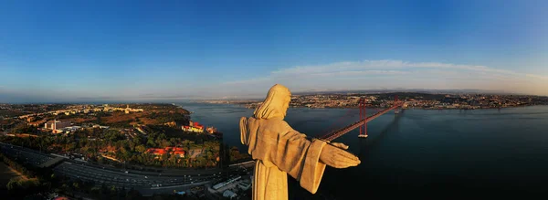 Letecký panoramatický pohled na svatyni krále Krista, Santuario de Cristo Rei s mostem 25 de Abril, visutý most, řeka Tagus, letecký výhled na bezpilotní letouny při východu slunce. Lisabon, Portugalsko — Stock fotografie