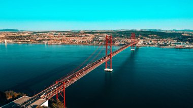 25 Nisan Köprüsü 'nün hava görüntüsü ya da insansız hava aracı fotoğrafı. Kırmızı köprü Lizbon ve Almada 'yı birbirine bağlıyor, Portekiz. Tagus Nehri.