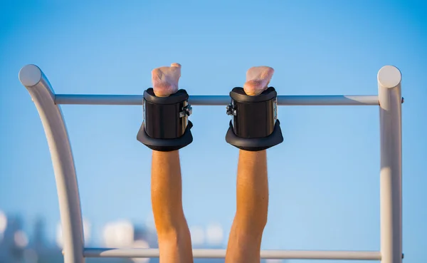 Man hanging upside down on the horizontal bar in anti gravity or inversion bootson the blue sky background. Sports equipment. Boots help to align the spine — Stock Image Man hanging upside down on the horizontal bar in anti gravity or inversion bootson the blue sky background. Sports equipment. Boots help to align the spine Stock Photo
