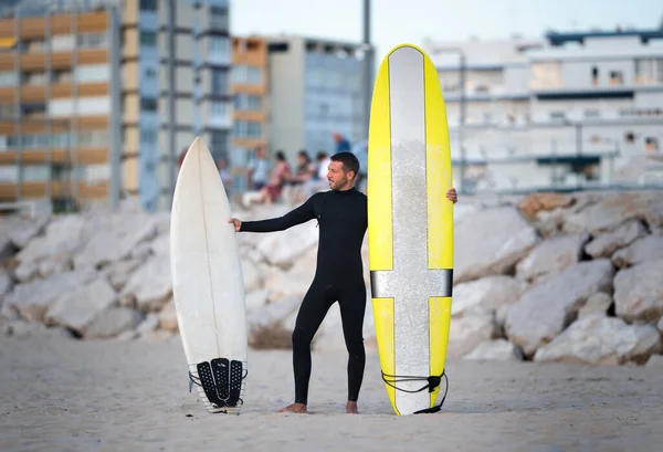 Πορτρέτο του σέρφερ σε μαύρο ζίπλες surfing wetsuit προσπαθώντας να επιλέξετε longboard ή shortboard — Φωτογραφία Αρχείου