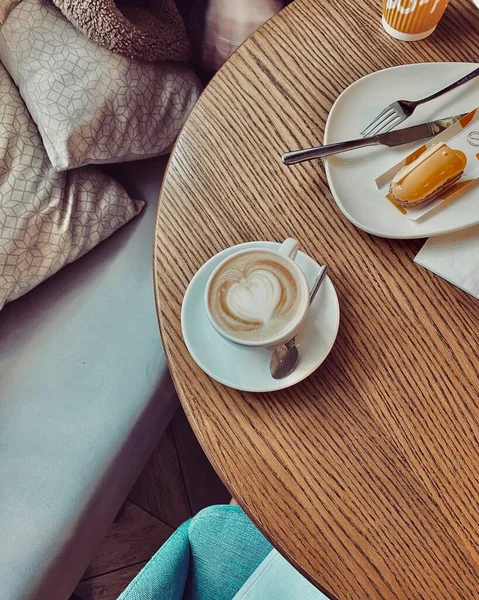 木製のテーブルにコーヒーを飲みながら朝食とソファでゆったり — ストック写真