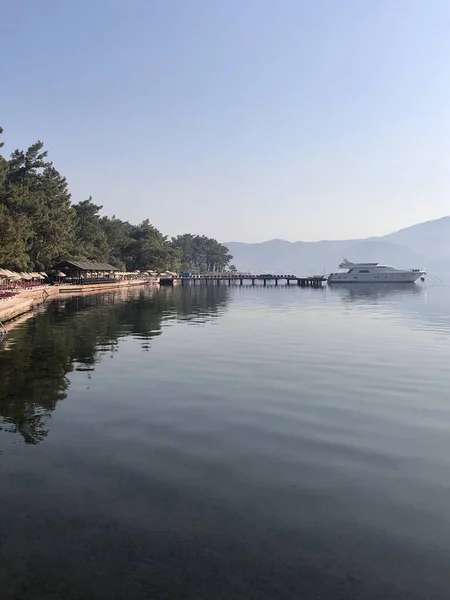Mavi deniz ve dağlarla deniz kenarında bir tekne