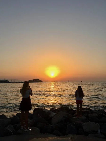 Plajda gün batımı, tropik bir ülkede kızıl gökyüzü ve insanlar.