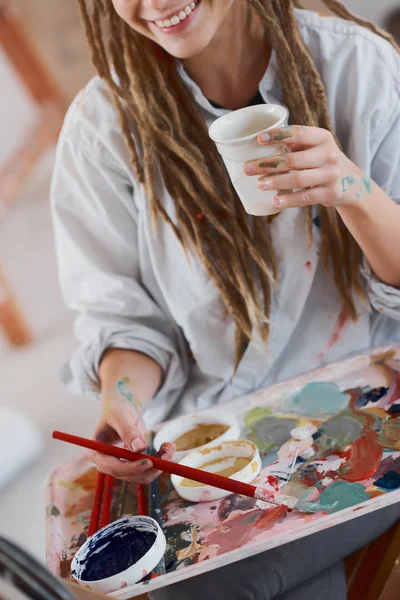 Künstlerisches Mädchen Trinkt Kaffee Während Atelier Sitzt Und Auf Staffelei — Stockfoto