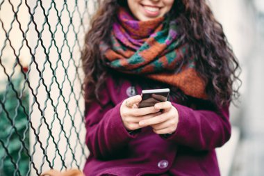 Kadının'ın el çit açık havada üzerinde otururken akıllı telefon tutarak yakın çekim.