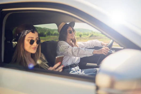 Dos Chicas Conduciendo Coche Una Conducción Otra Utilizando Teléfono Inteligente — Foto de Stock