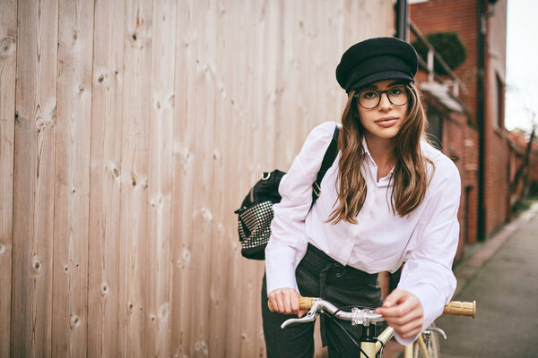 Portrait of beautiful brunette holding bicycle. Wooden background.