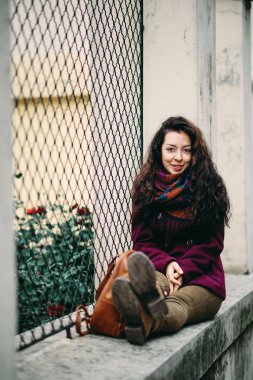 Poz ve çit sokakta oturan kız.