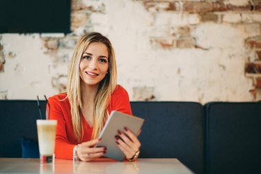 Beyaz kadın tablet kafede oturan ve kahve içme kullanma.
