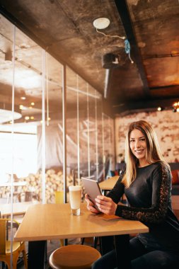 Beyaz kadın tablet kafede oturan ve kahve içme kullanma.