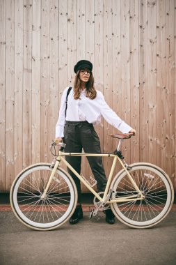 Güzel esmer holding Bisiklet portresi. Ahşap arka plan.
