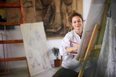 Sanatsal kız oturan stüdyo ve boya şövale üzerinde.