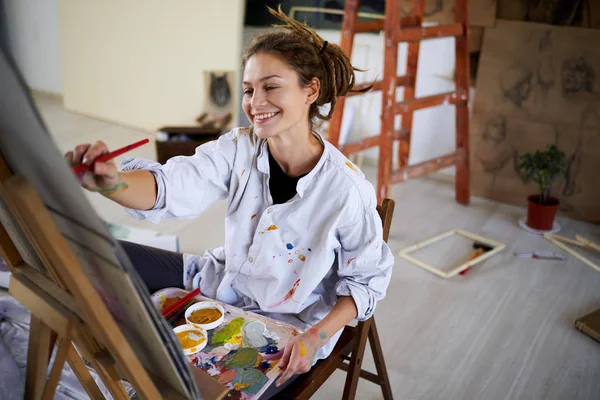 芸術的な女の子に座ってスタジオ 塗料イーゼル — ストック写真