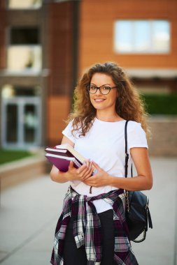 Omuz silah ve çanta kitapları ile kampus içinde kız öğrenci.
