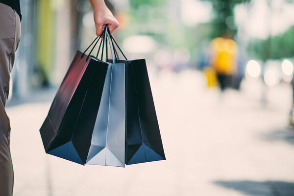 Закрыть женскую руку, держа в руках сумки для покупок, гуляя по улице
.