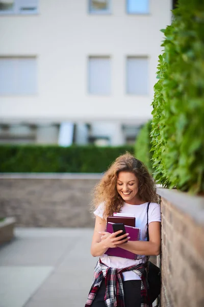 Estudiante Usando Teléfono Inteligente Sosteniendo Libros Mientras Camina Campus — Foto de Stock