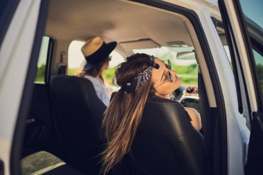 İki kadın arabada sürüş. Süren ve diğer araba koltuğuna kıvrılarak.