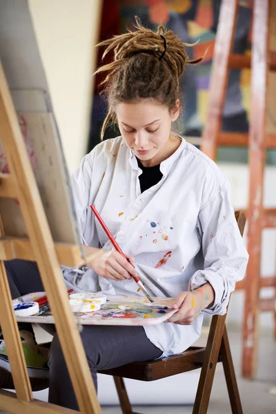 Künstlerisches Mädchen Sitzt Atelier Und Malt Auf Staffelei — Stockfoto