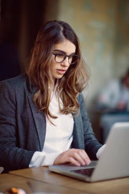 Kafede oturan ve dizüstü bilgisayar kullanarak genç modern kadın.