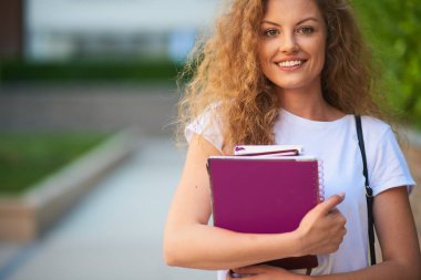 Omuz silah ve çanta kitapları ile kampus içinde kız öğrenci.