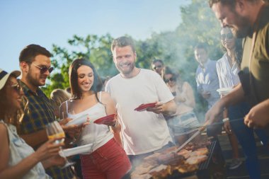 Bir grup insan mangal yapıyor, sohbet ediyor, içiyor ve yemek yiyor.. 