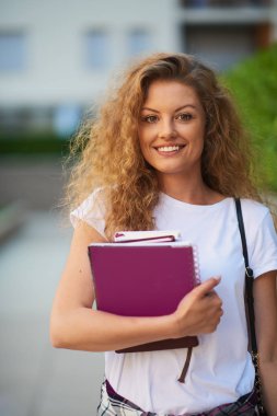 Omuz silah ve çanta kitapları ile kampus içinde kız öğrenci.