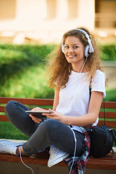 Giovane Donna Seduta Sulla Panchina Con Gambe Incrociate Ascoltando Musica — Foto Stock