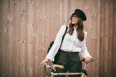 Güzel esmer holding Bisiklet portresi. Ahşap arka plan.