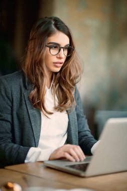 Kafede oturan ve dizüstü bilgisayar kullanarak genç modern kadın.