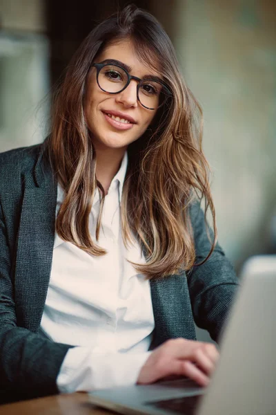 Kafede oturan ve dizüstü bilgisayar kullanarak genç modern kadın.