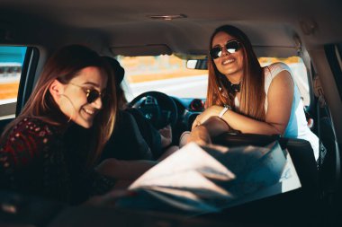 Eğlenceli roadtrip Haritaya bakarken iki genç kadın. Üçüncü kız sürüş.