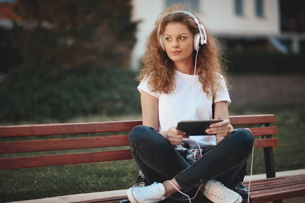 Mujer Joven Sentada Banco Con Las Piernas Cruzadas Escuchando Música —  Fotos de Stock