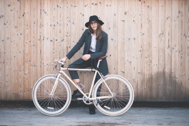 Güzel esmer holding Bisiklet portresi. Ahşap arka plan.