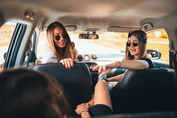 Три женщины наслаждаются поездкой. Они разговаривают, сидя в машине.
.