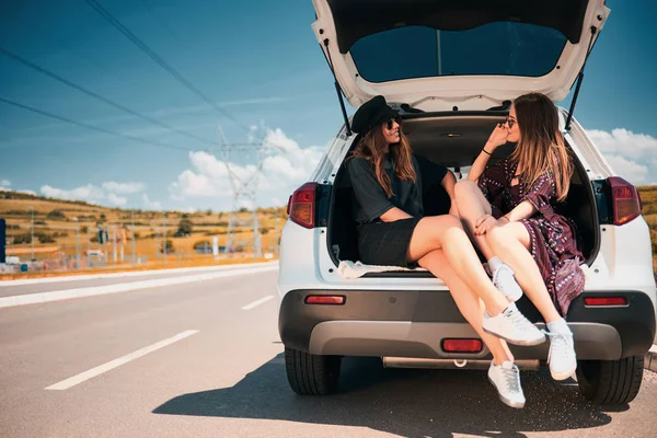 Duas Raparigas Sentadas Bagageira Falar Carro Estacionado Estrada — Fotografia de Stock