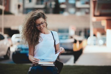 Bankta oturan ve kitap okuma kız öğrenci.