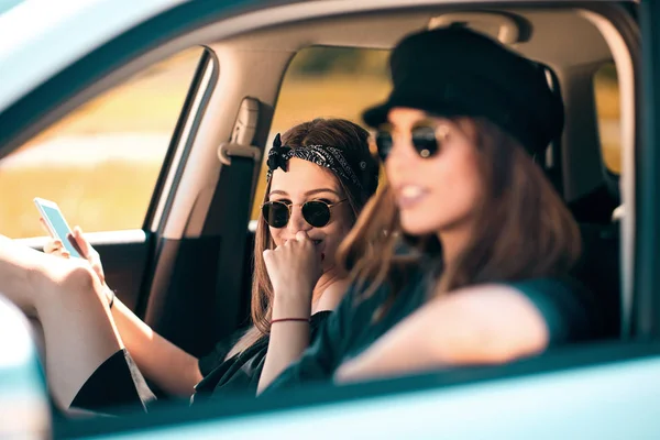 两个女孩在车里开车 一个女孩驾驶和其他使用智能手机短信 — 图库照片