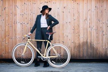 Güzel esmer holding Bisiklet portresi. Ahşap arka plan.