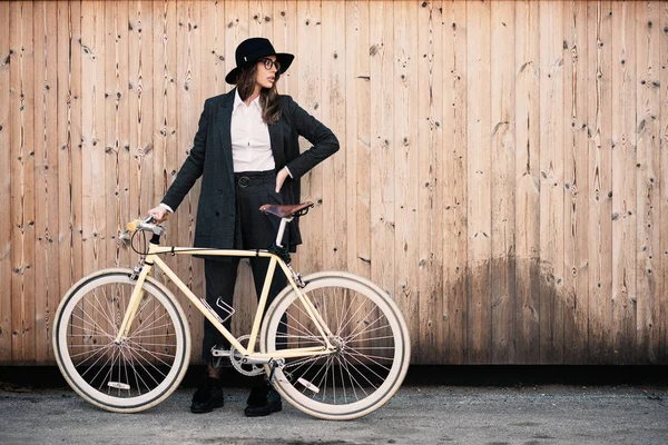 Güzel esmer holding Bisiklet portresi. Ahşap arka plan.
