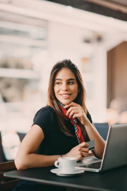 Kafede otururken alışveriş için kredi kartı ve dizüstü bilgisayar kullanan mutlu genç kadın.