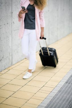 Bagaj taşıma ve karakola yürürken akıllı telefon kullanan kadın.